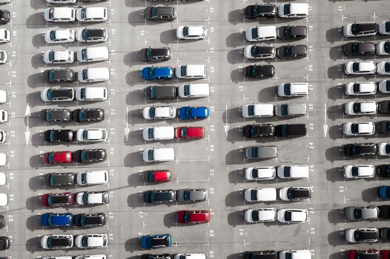 Vogelperspektive auf einen großen Parkplatz bei Gebrauchtwagen Ankauf Wedel, der mit Reihen weißer Autos gefüllt ist.